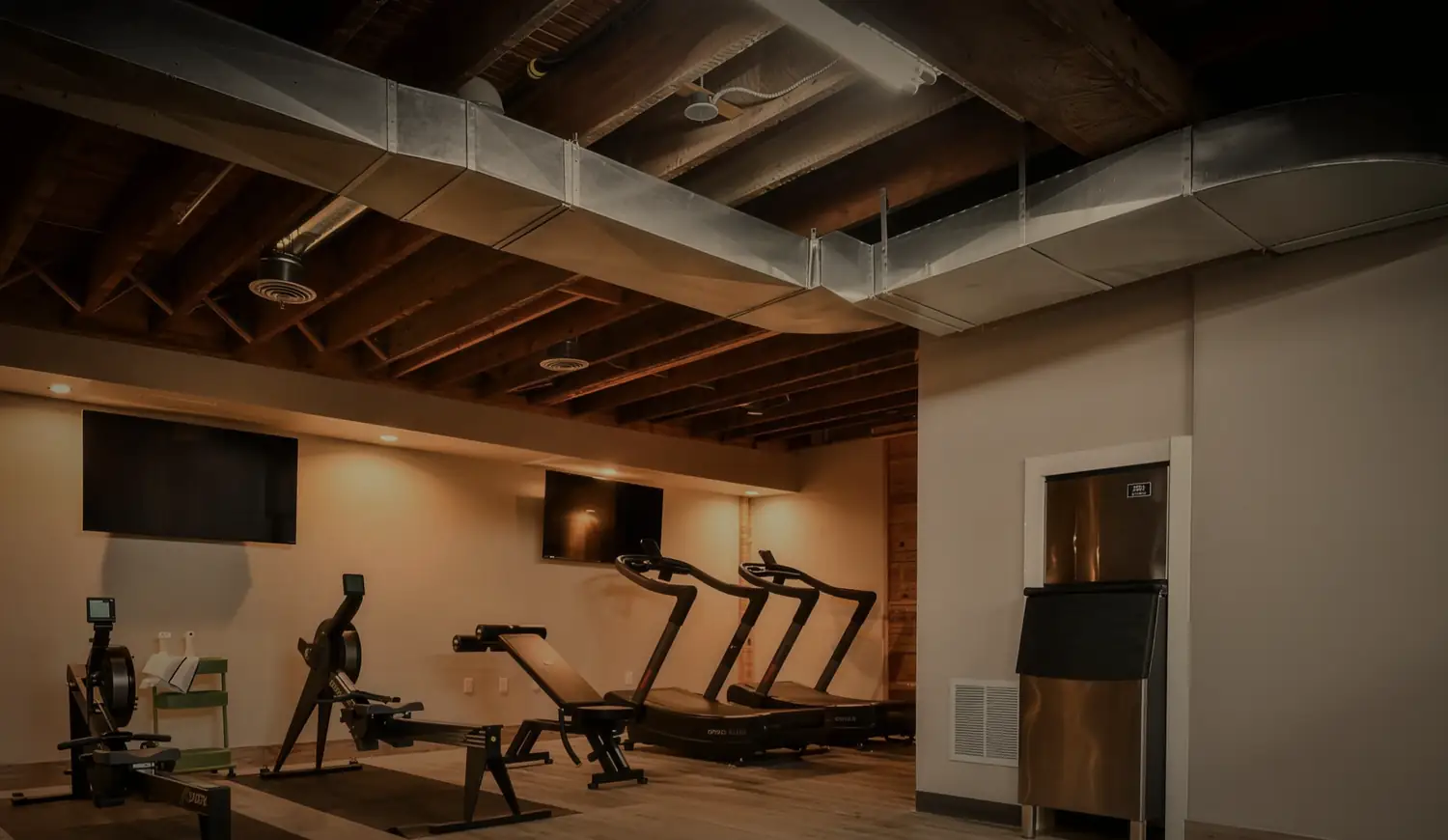 The cardio room under exposed timber beams and warm downlights.