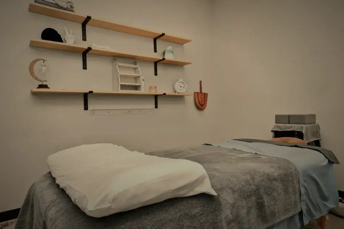 The massage room, table made up, shelving on the wall.